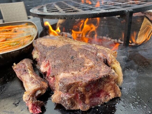 Côte de bœuf saisie sur la plancha, flammes en arrière-plan