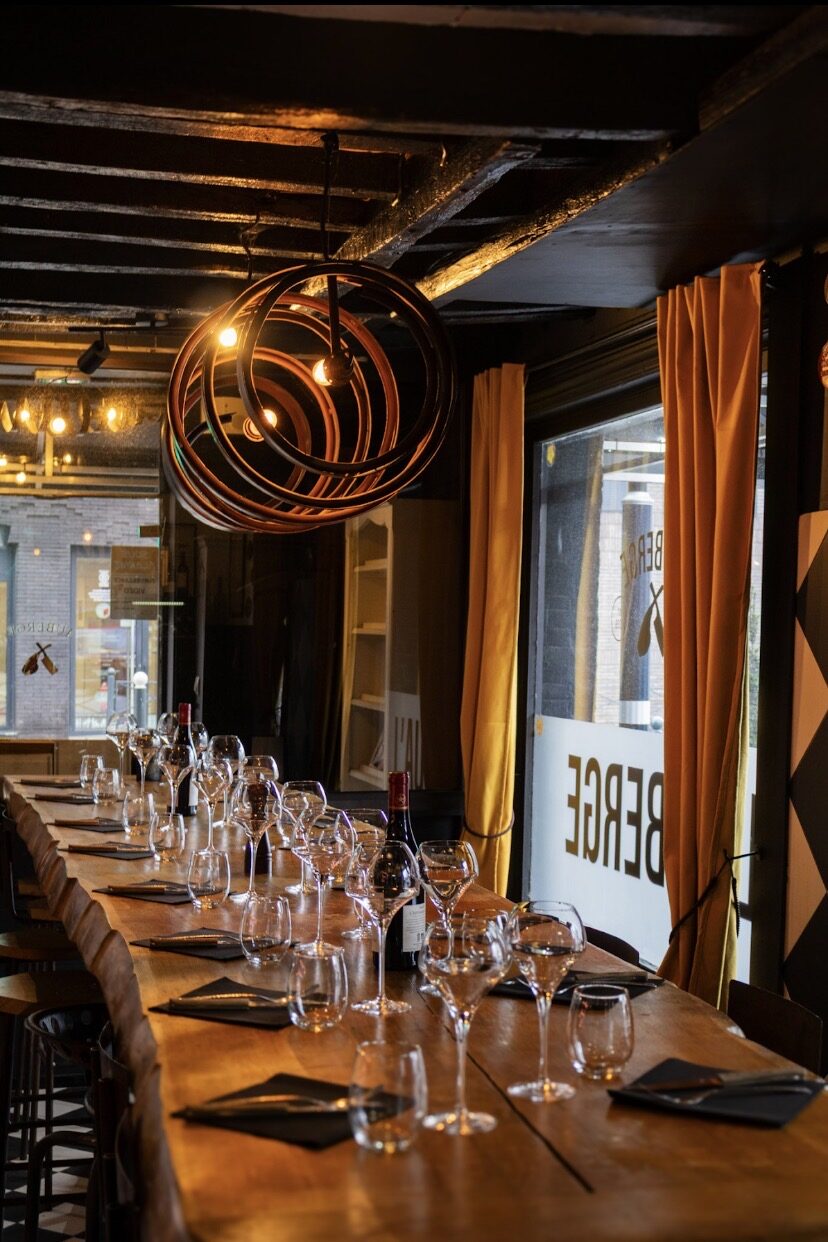 La grande table d'hôte en chêne sous le lustre en cerclages de tonneau